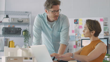 Männliche-Und-Weibliche-Architekten-Im-Büro-Arbeiten-Am-Schreibtisch-Am-Laptop-Und-Treffen-Sich-Gemeinsam