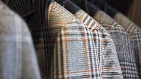 patterned tailored tweed jackets hanging in wooden wardrobe, close up