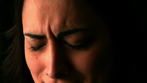 Upset-brunette-with-eyes-closed-on-black-background