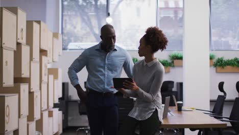 Diverse-male-and-female-business-colleagues-talking-and-using-digital-tablet-in-office