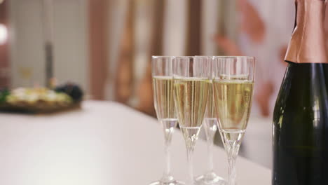 side view of a champagne bottle and crystal glasses with champagne on a table at a bachelorette party