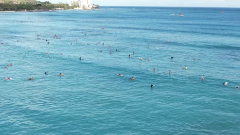 sets of waves roll in as surfers line up to catch a wave at a popular tropical beach surfing location