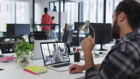 Middle-eastern-man-talking-on-video-call-with-female-office-colleague-on-laptop-at-office