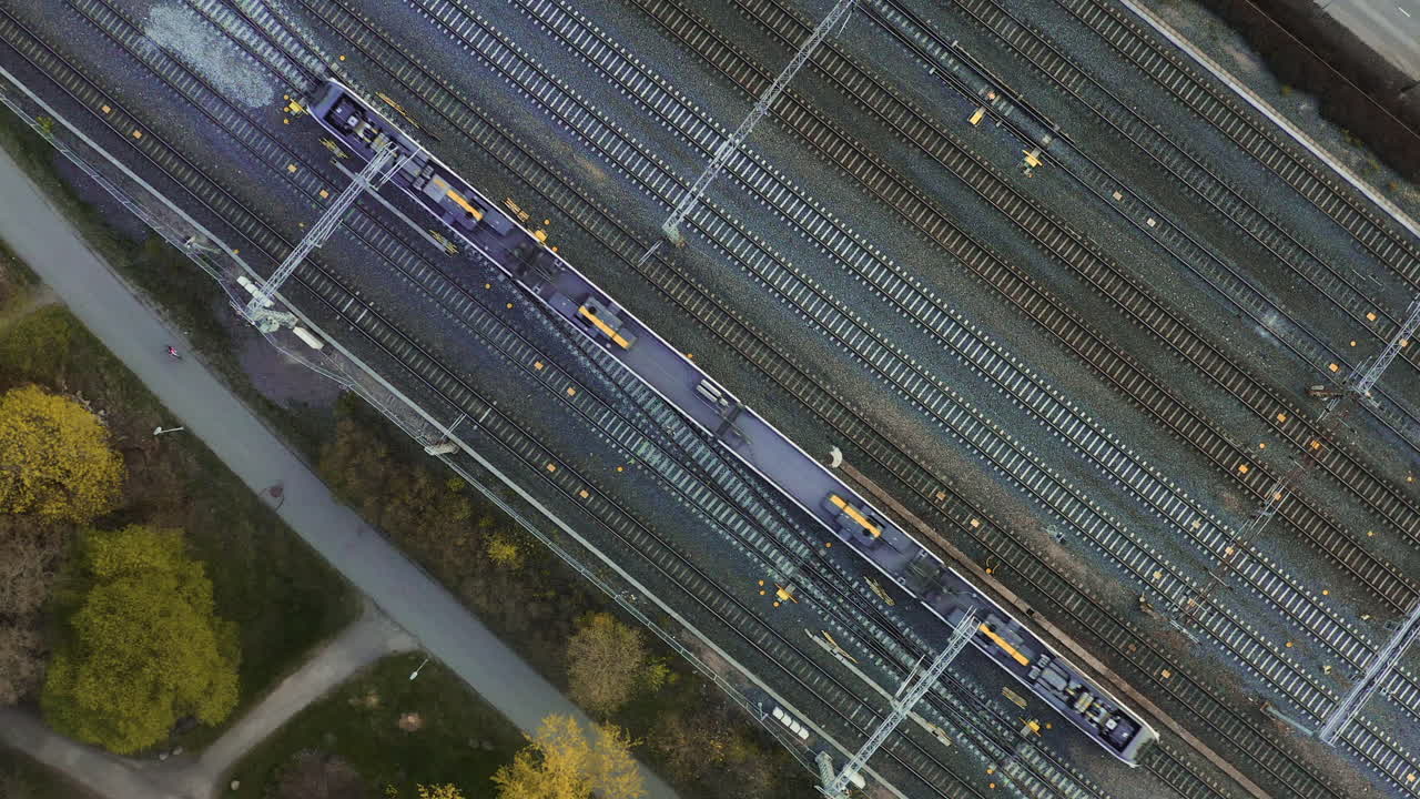 Aerial, top down, drone shot of a train on the main railway, between Helsinki and Pasila railway stations, sunny day, in Helsinki, Finland