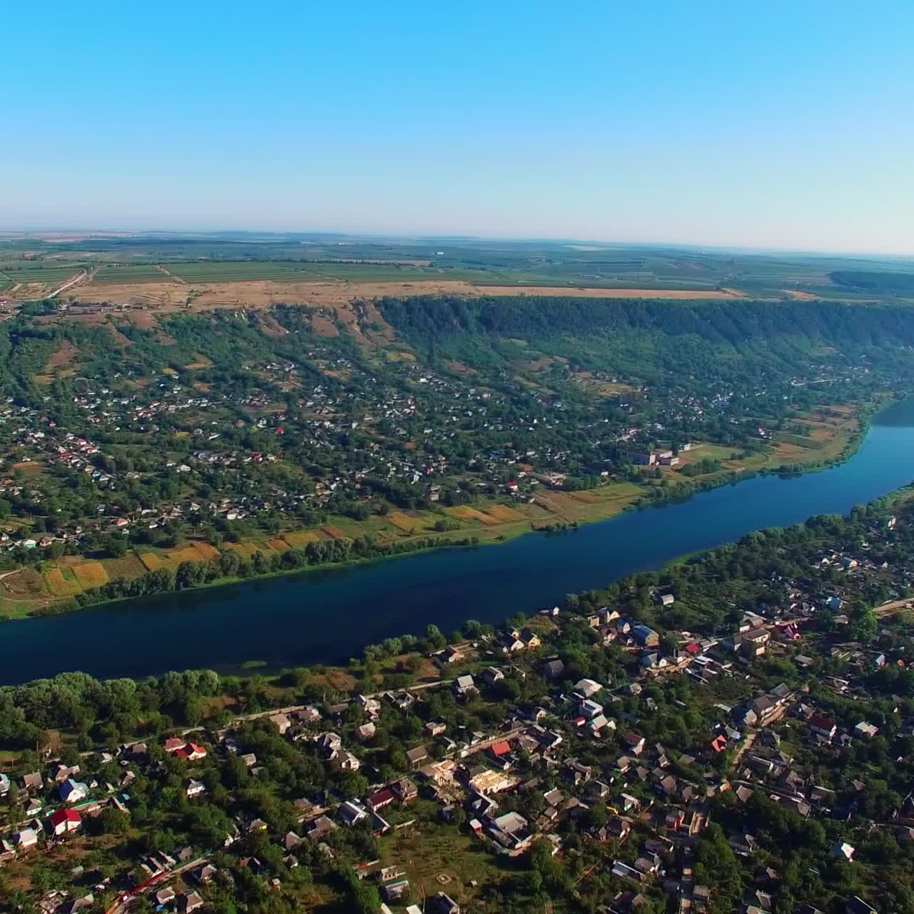 Scenery of the city built on the both banks of the beautiful river. Amazing view of the landscape on sunny summer day from air