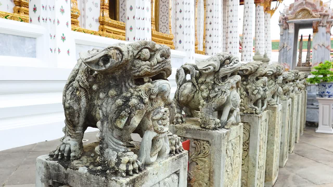 Stone lion statues line the temple walkway, showcasing intricate carvings and historical artistry in bright daylight