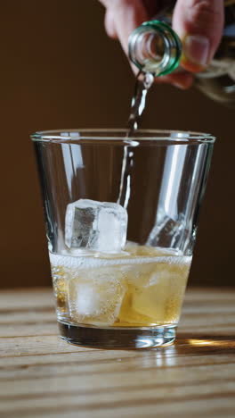 pouring a drink into a glass with ice