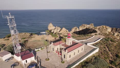 aerial of the lighthouse of lagos, portugal overlooking the cliffs of the sea