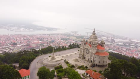 Iglesia-Icónica-En-La-Cima-De-Una-Colina-Con-La-Ciudad-De-Viana-Do-Castelo-Abajo,-Vista-Aérea-De-La-órbita