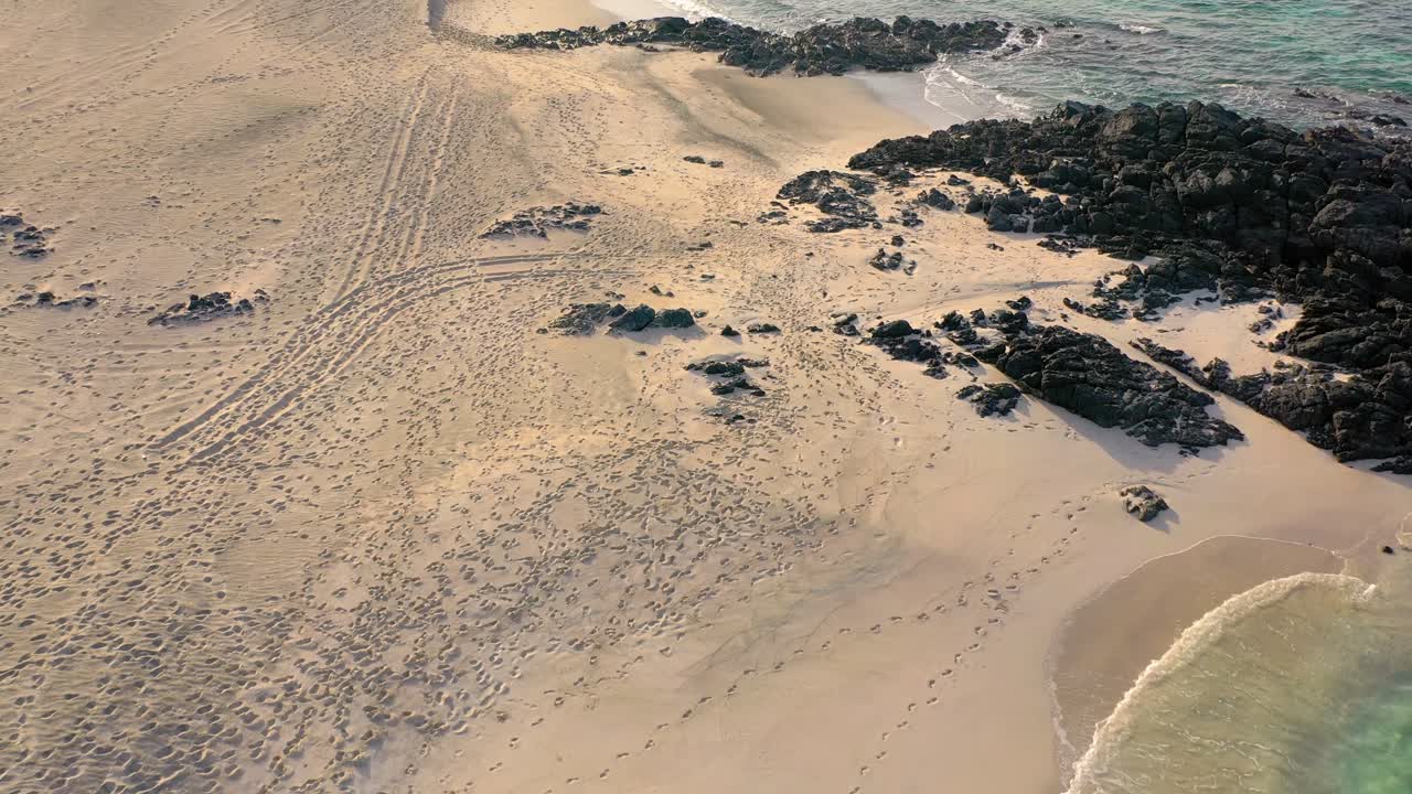 타이어 자국과 발자국으로 뒤덮인 모래 해변 위의 공중 촬영
