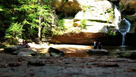 Ground-level-shot-of-a-beautiful-waterfall-with-a-few-hikers-enjoying-the-view