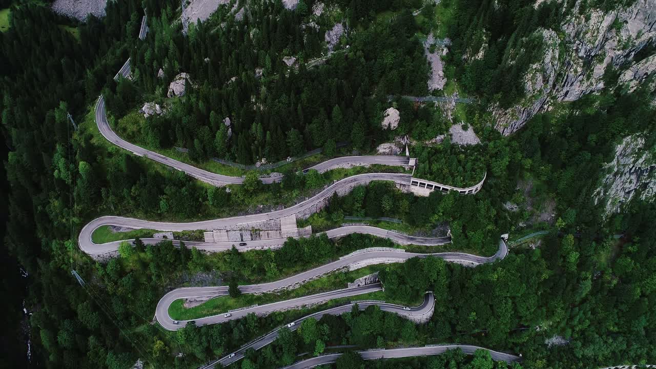Steep hairpin turns snake through alpine forest on dramatic Italian hillside