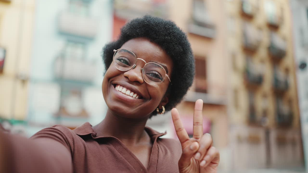 Positive African American dark haired woman taking selfie on the street