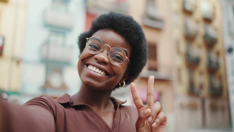 positive african american dark haired woman taking selfie on the street