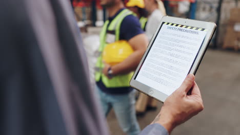 reading safety precautions on a tablet in a warehouse