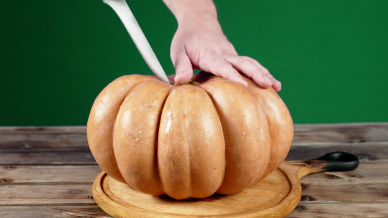 칼을 들고 있는 남성의 손이 호박 조각을 잘라냈습니다.