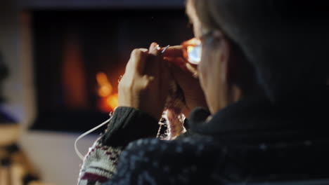 elderly lady knits a warm scarf by the fireplace 4k video