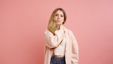 young woman massaging neck on pink background