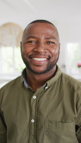 video vertical del retrato de un feliz hombre afroamericano mirando a la cámara y sonriendo
