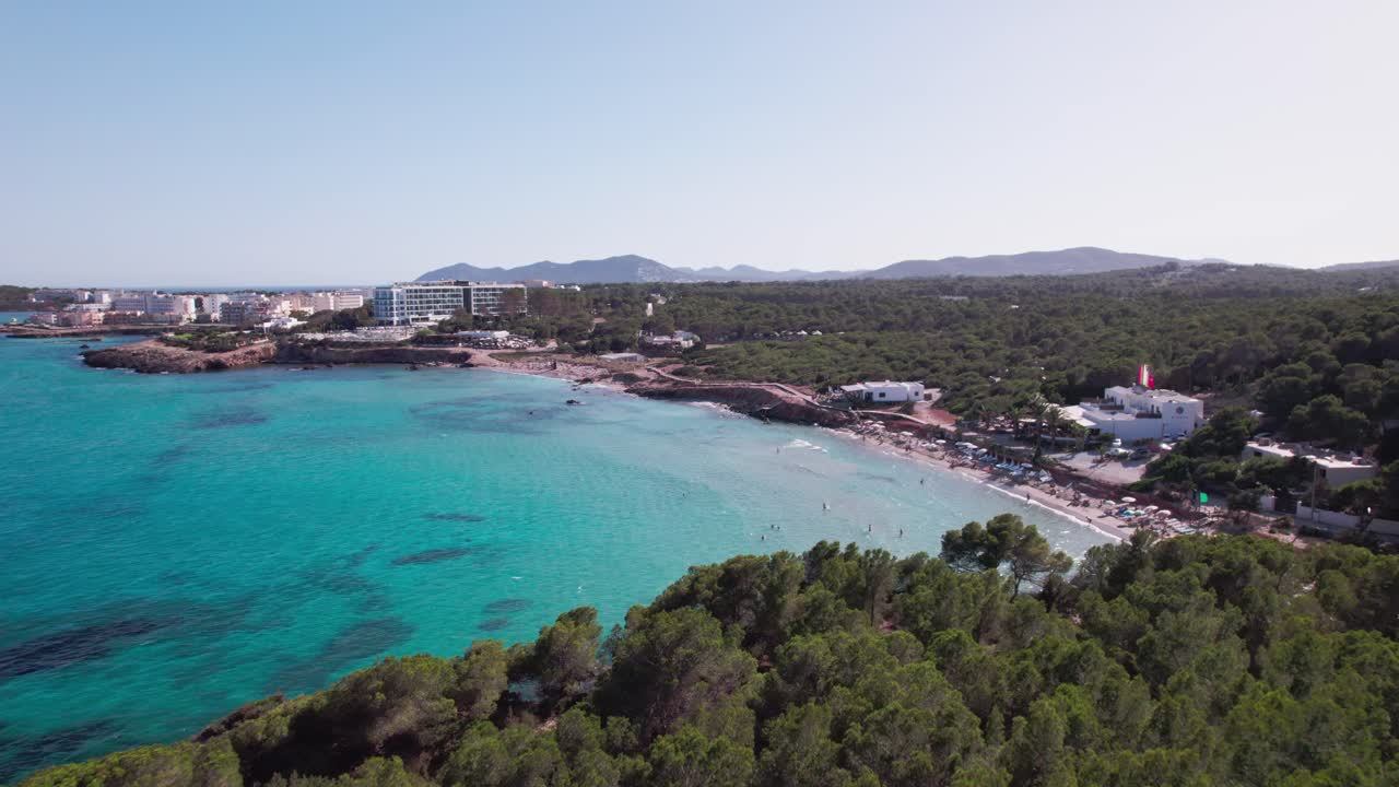 vuelo aéreo sobre una hermosa playa en un día soleado con agua azul y árboles verdes en ibiza