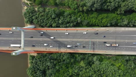 City-car-moving-at-highway-bridge-on-background-smooth-river-surface-drone-view