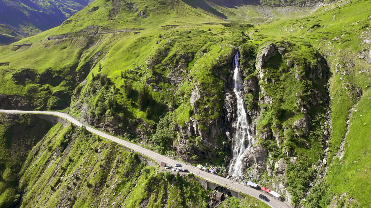 Vista aerea con drone della natura in Romania. Strada Transfăgărășan sui Monti Carpazi con cascata vicino alla strada, pendii rocciosi con vegetazione