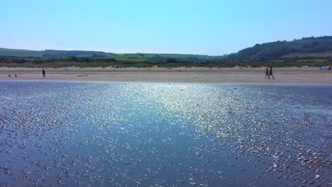 Luftbewegung-Eines-Paares,-Das-An-Einem-Nassen-Strand-Entlang-Läuft