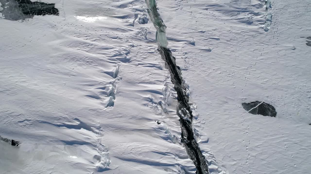눈에 인 바이칼 호수의 얼어붙은 얼음 표면의 깊은 균열 위의 공중. 자연 랜드마크. 겨울 풍경. 인기 있는 관광지. 높은 각도 전망.