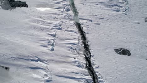 aérea por encima de la profunda grieta en la superficie de hielo congelado cubierto de nieve del lago baikal. punto de referencia natural. paisaje de invierno. destino turístico popular. vista de alto ángulo.