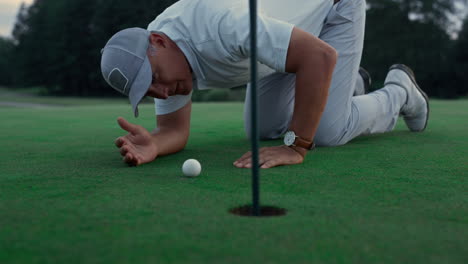 professional golf player inspect golfing ball hole on green grass course field.