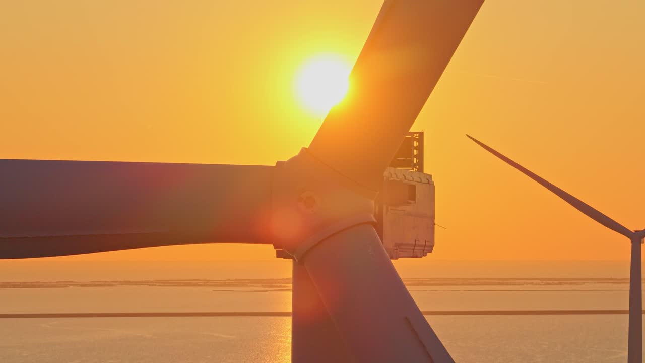 Offshore wind turbine rotating against beautiful golden sunset