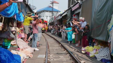 tourists photographing a train in a thai market