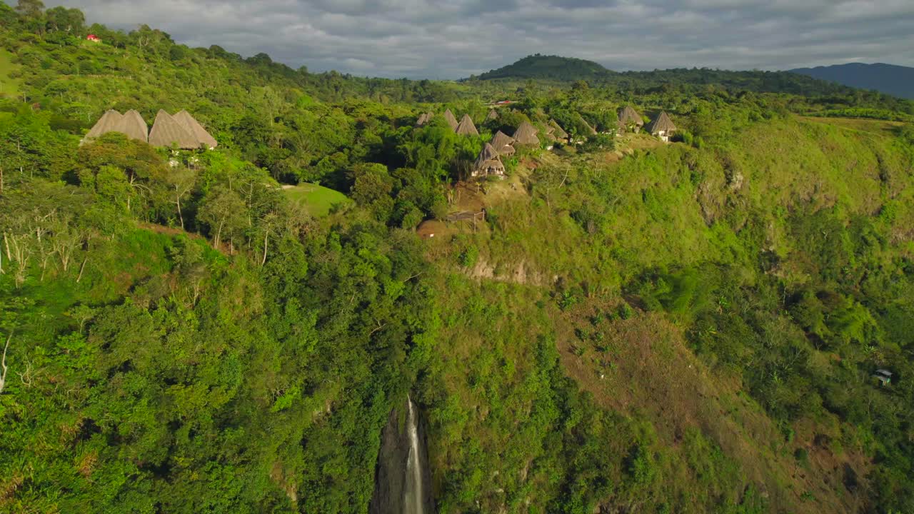 espectaculares cabañas de madera en el borde de un cañón tropical donde una cascada cae al amanecer