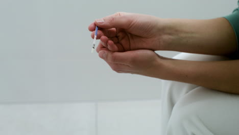 Hände-Halten-Schwangerschaftstest-Im-Badezimmer