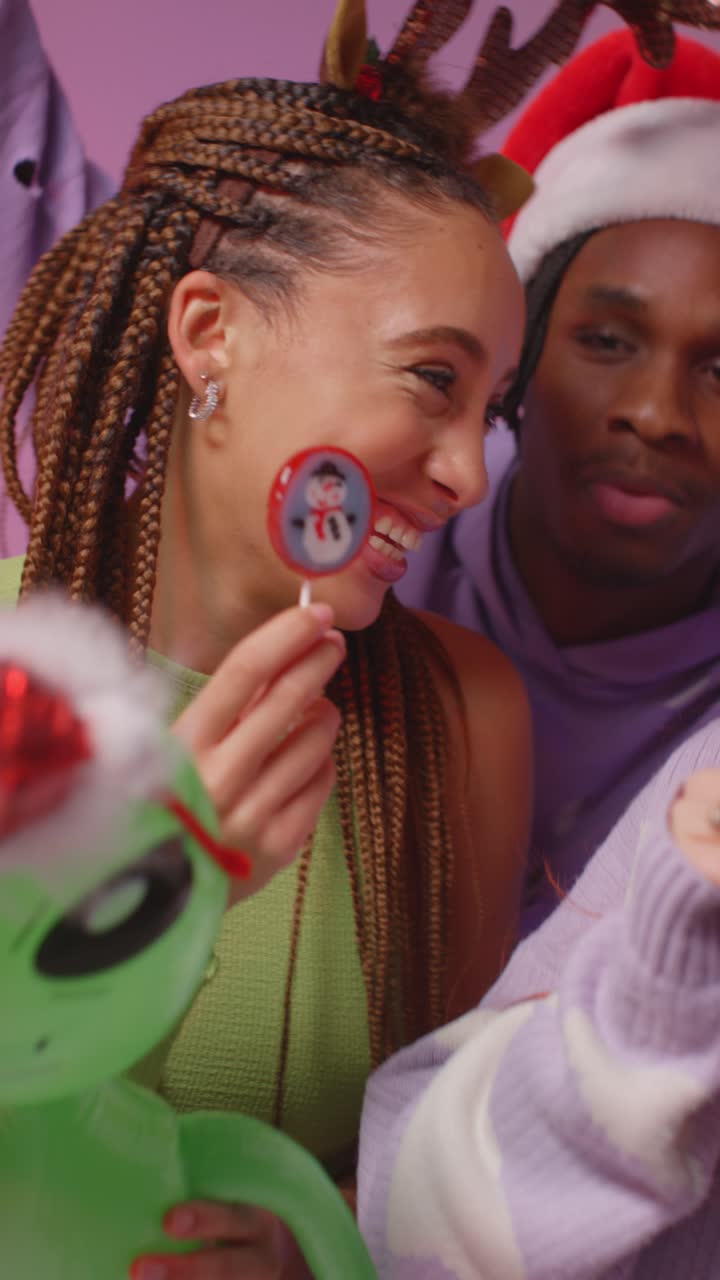 una toma vertical de estudio de video de amigos de la generación z bailando en una fiesta de navidad con sombrero de papá noel y cuernos de reno 1