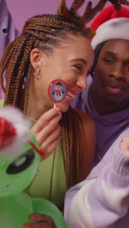 Vertical-Video-Studio-Shot-Of-Gen-Z-Friends-Dancing-At-Christmas-Party-Wearing-Santa-Hat-And-Reindeer-Antlers-1