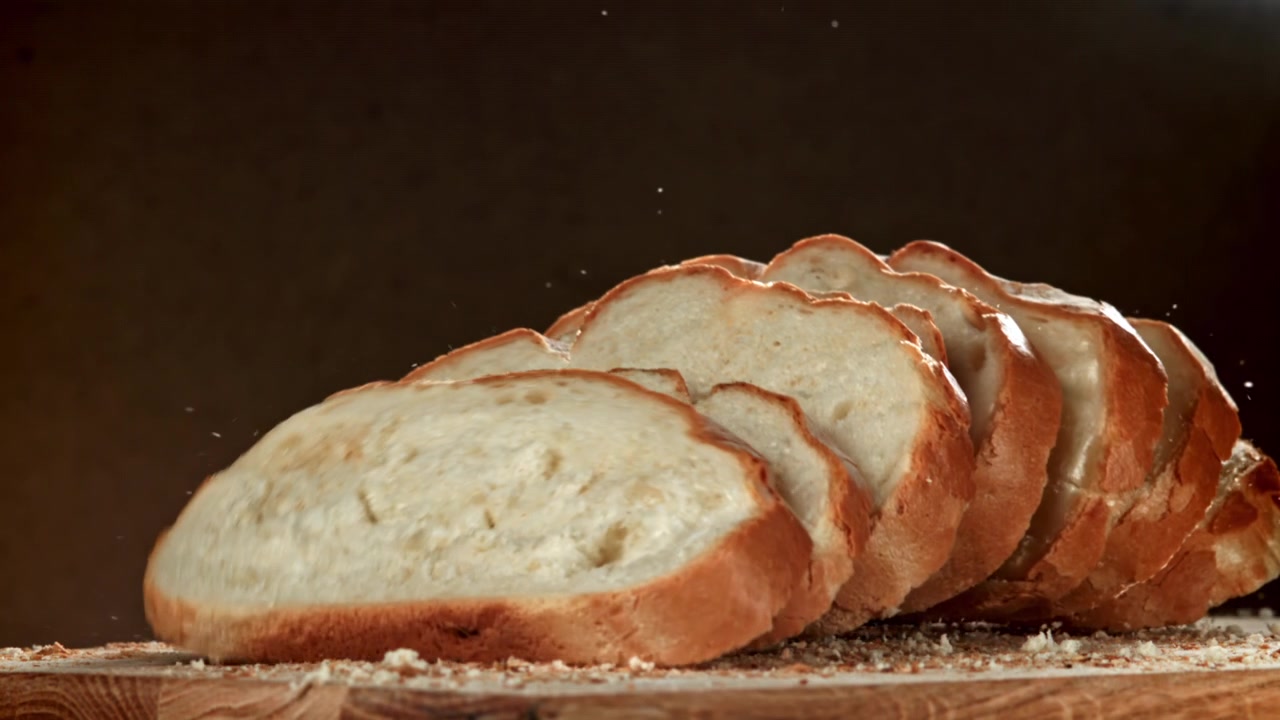 Pane bianco a fette che cade al rallentatore su una tavola di legno
