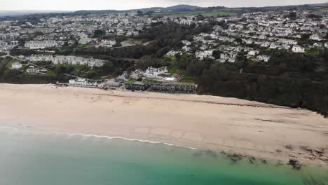 Toma-Panorámica-Izquierda-De-Carbis-Bay-Que-Muestra-La-Playa,-El-Hotel-Y-La-Ciudad-En-Cornualles,-Inglaterra