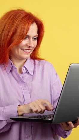woman with red hair smiling and using laptop