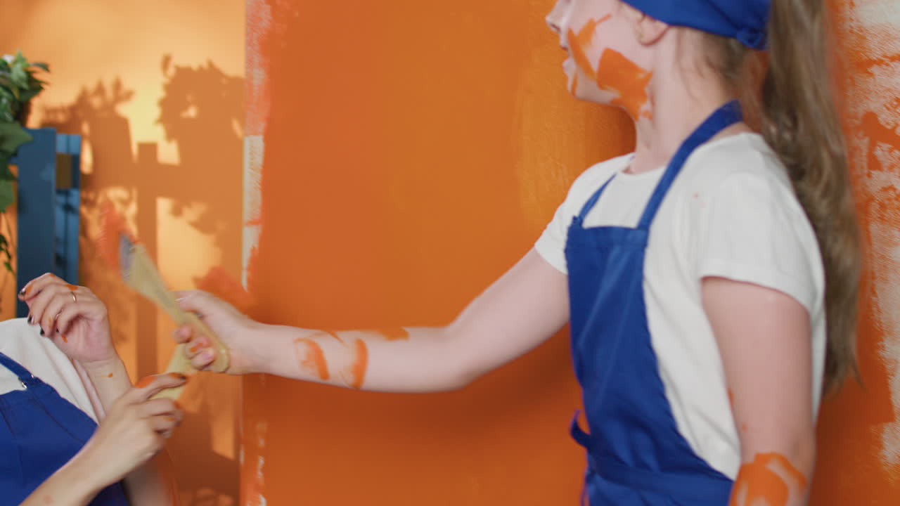 Women painting a wall orange