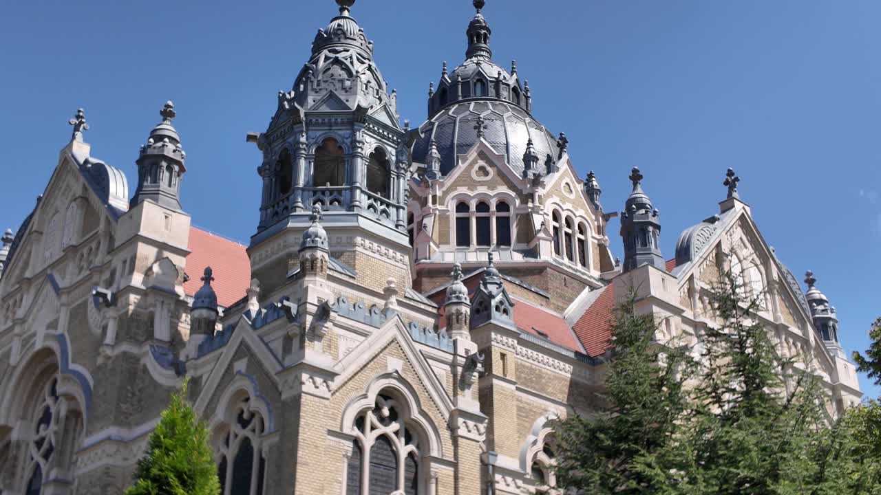Exterior shot of Szeged Synagogue with trees in the foreground, emphasizing architecture, heritage, and landscape