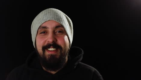 Young-stylish-man-with-happy-face,-smiling-in-front-of-camera-with-a-confident-expression-in-dark-room