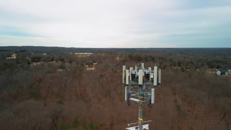 aerial reverse shot of cell phone tower in middle of forest