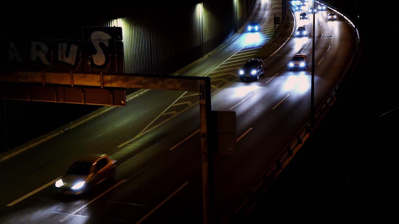Cars driving on national highway (german Autobahn) in Berlin at night, street sign in foreground, car headlights passing by