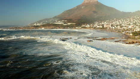 olas oceánicas espumosas que llegan a la costa de la bahía de campamentos y las playas de bakoven en ciudad del cabo, sudáfrica