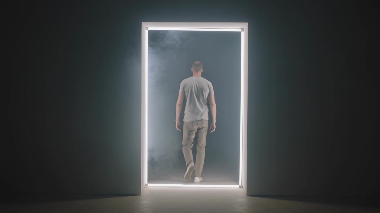 Walking man moving through LED doorway into smoky studio, LED frame drawing him, wearing grey tee