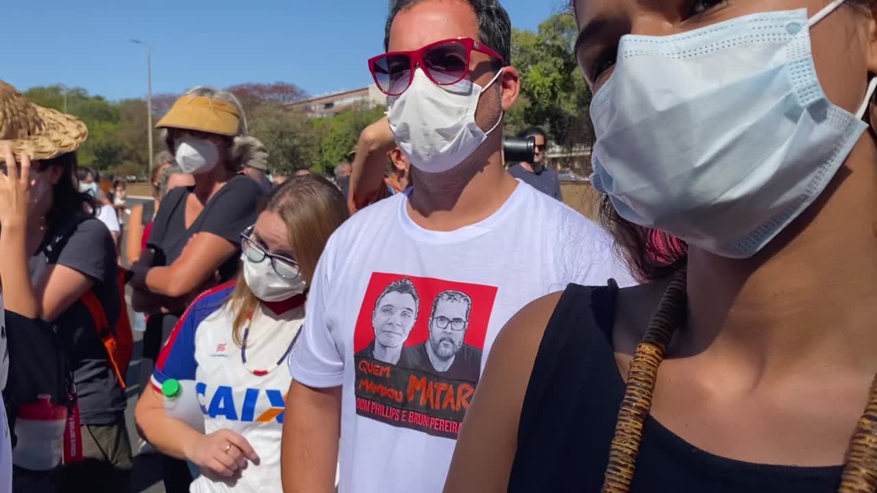 sliding shot ending on a man his shirt with the image of the two murdered journalists dom phillips and bruno pereira in the amazon in brazil