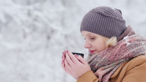 a woman drinks hot tea in the winter forest