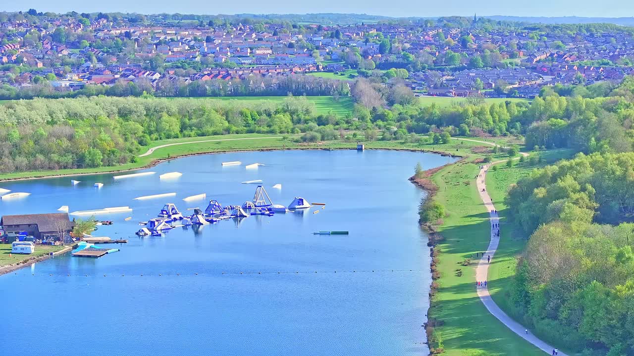 Aerial: aquatic fun park on the lake during the day in Rother Valley Country Park in the Metropolitan Borough of Rotherham, South Yorkshire, England, crane up drone shot