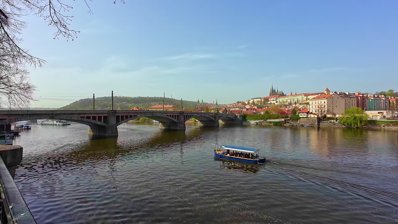 un barco turístico navega bajo un puente en el río vltava en praga, vista estática